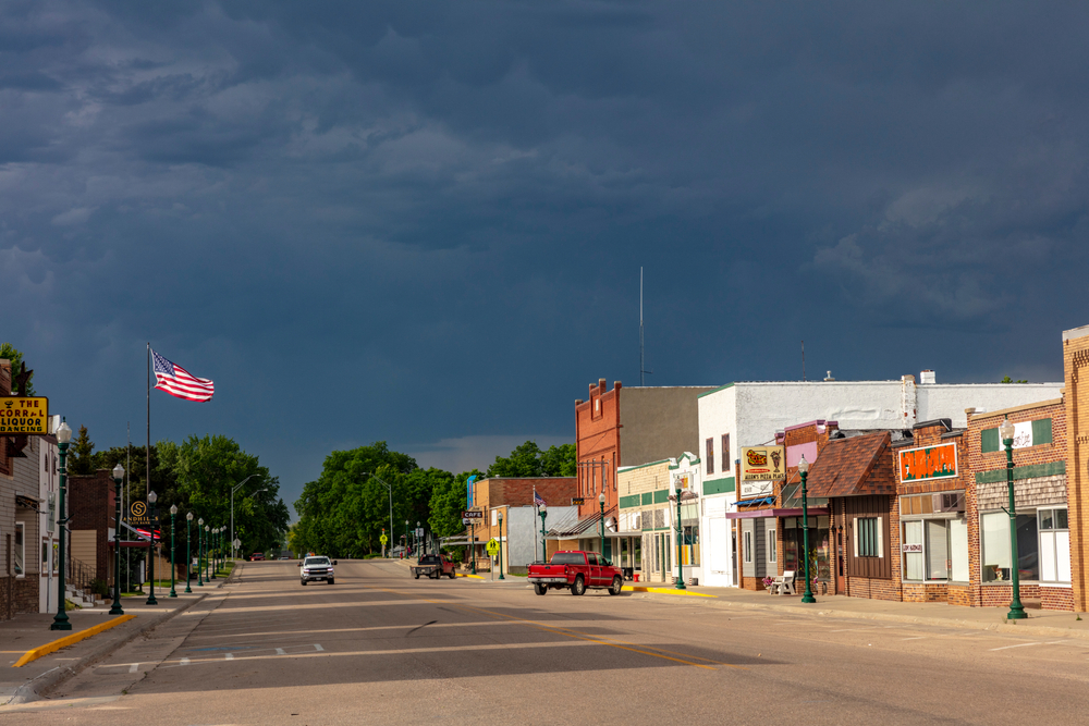 A historic main street in a small town in Nebraska as a storm rolls in. You can see historic old brick buildings that are shops and restaurants. 