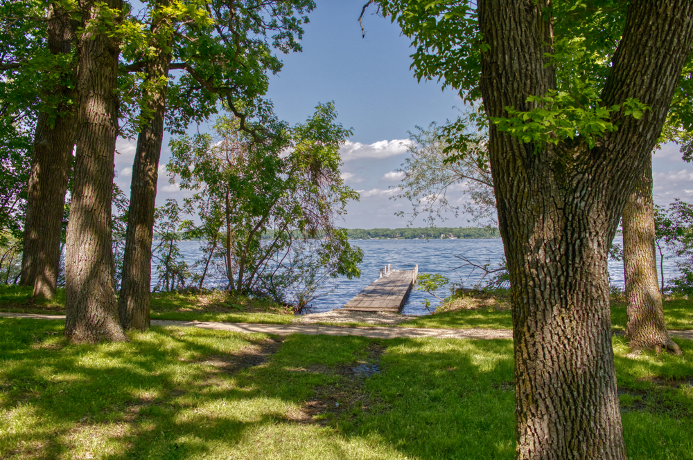 Gull Point State Park is a plce to go camping in Iowa. The picture shows trees and a broadwalk going out on the lake. 