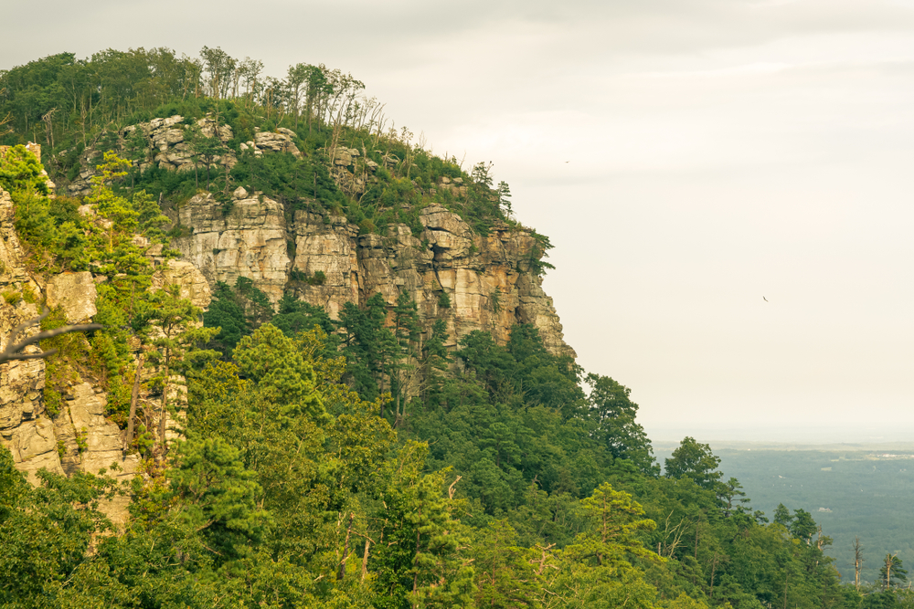 The Knob at Pilot Mountain State Park. Its a large rock with trees down the side you can see water in the background. 
