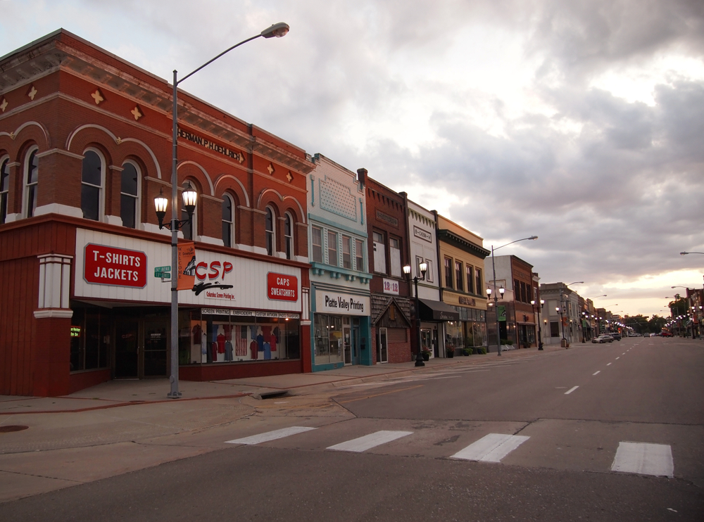 A main street in one of the historic towns in Nebraska where you can see old brick buildings, sidewalks, and streetlights. 