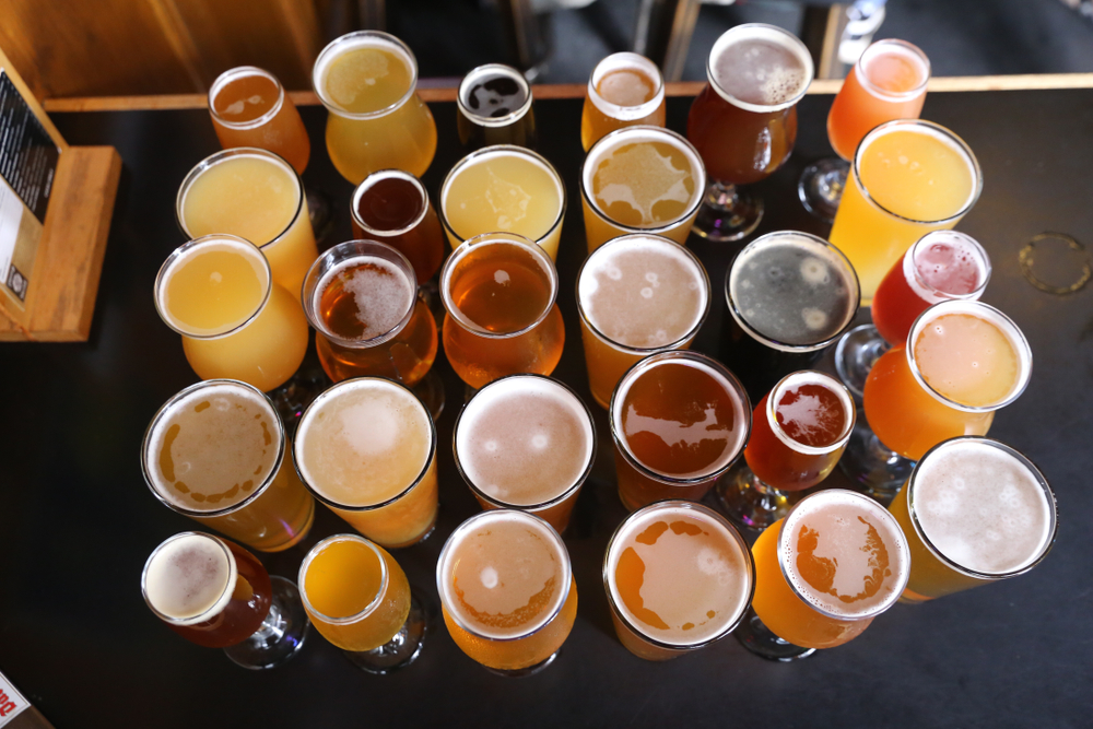 A huge selection of craft beers of every different color on a table. 