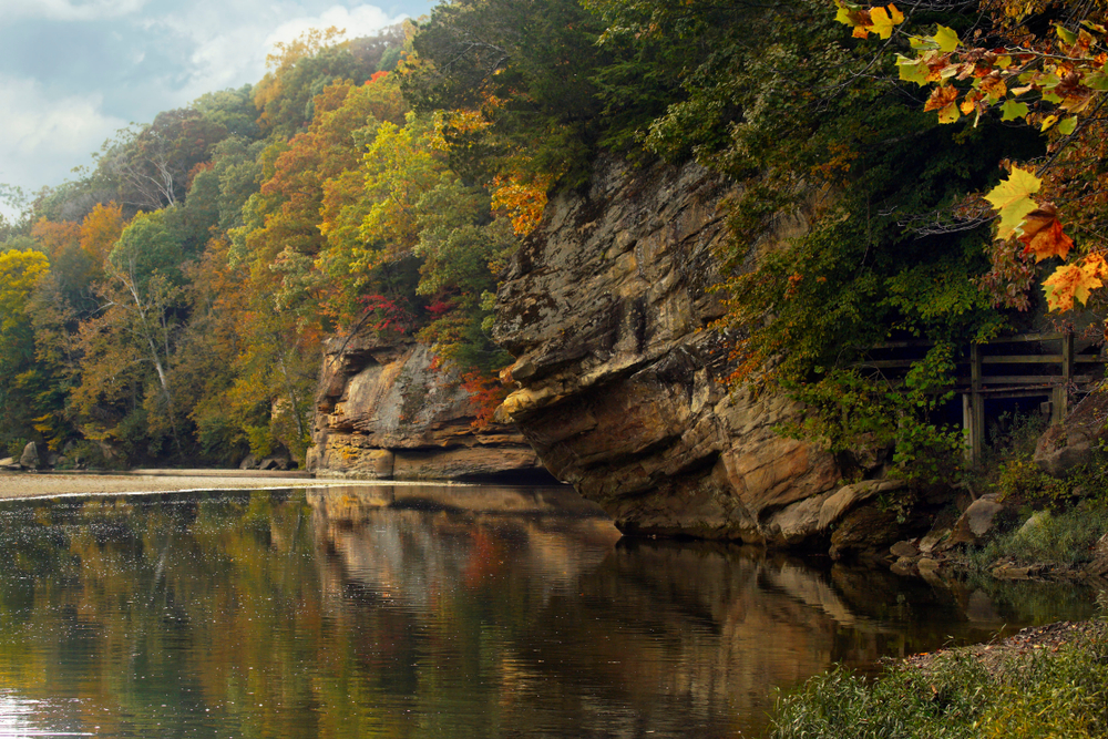 Cliffs overhanging a lake with fall colors all around the lake. 