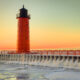 Winter view of red lighthouse with orange sunset in background, one of the lighthouses in Wisconsin