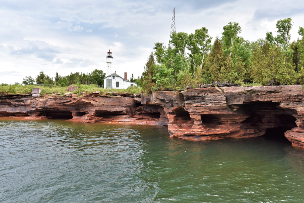 Water Caves and Lighthouse on Devil's Island on Lake Superior. The picture shows the caves and the white tower and house on the island. 