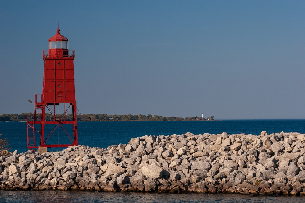 A red box lighthouse sitting on a skelton plith on a rocky outcrop 