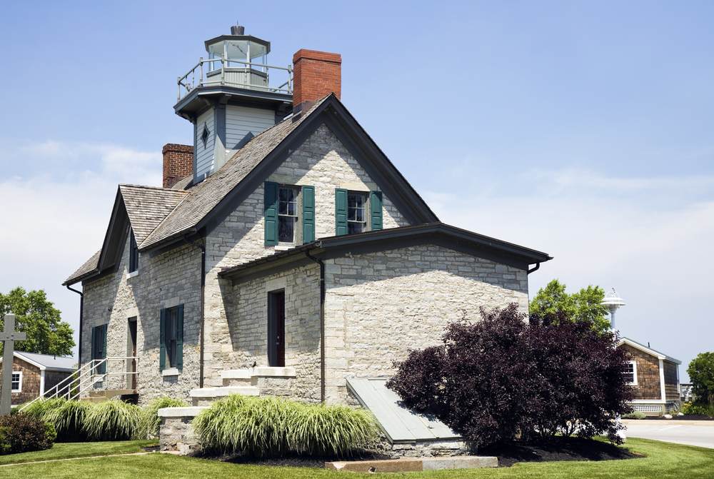 A grey buildign with a lighthouse coming out the top. The building is surrounded by shrubs.  