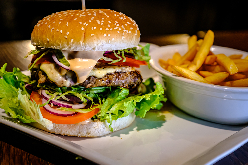 Fresh juicy burger with fried potatoes on a white plate in one of the best restaurants on Michigan City 