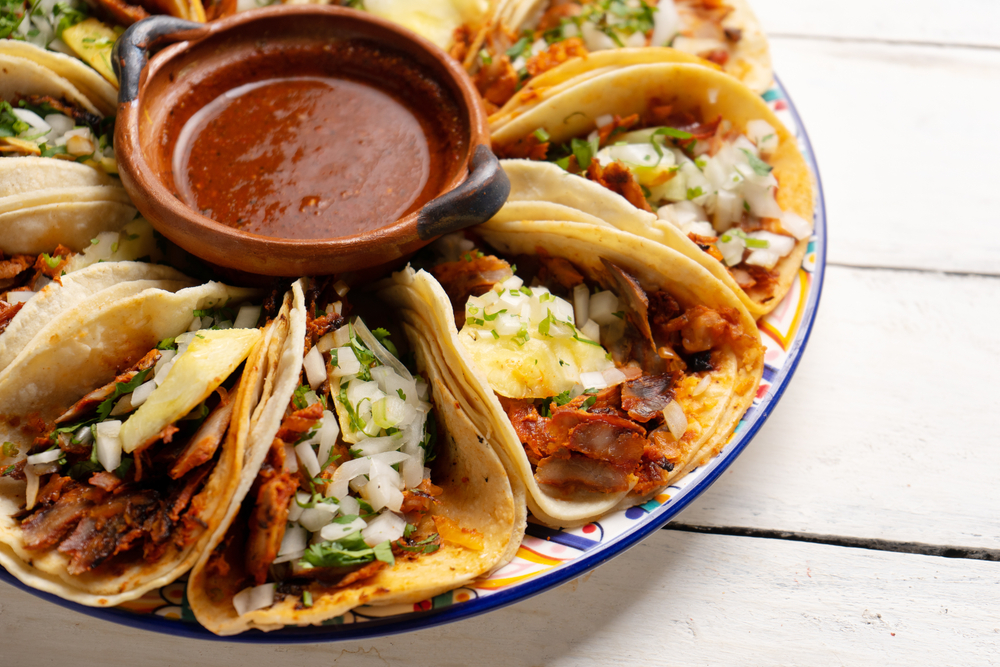 Traditional mexican pork tacos called "Al pastor" with pineapple on white background. In an article about restaurants in Michigan City 