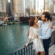 A couple stands holding each other overlooking the river on a date night in Chicago.