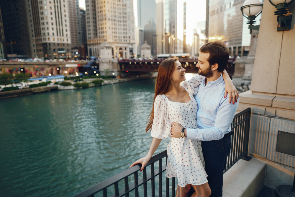 A couple stands holding each other overlooking the river on a date night in Chicago.