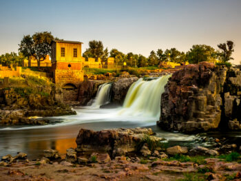 Shot of the waterfalls in front of the old mill in Falls Park, one of the best things to do in Sioux Falls, SD.