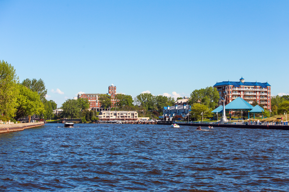 View of the St. Joseph River with people boating and downtown buildings in the background.