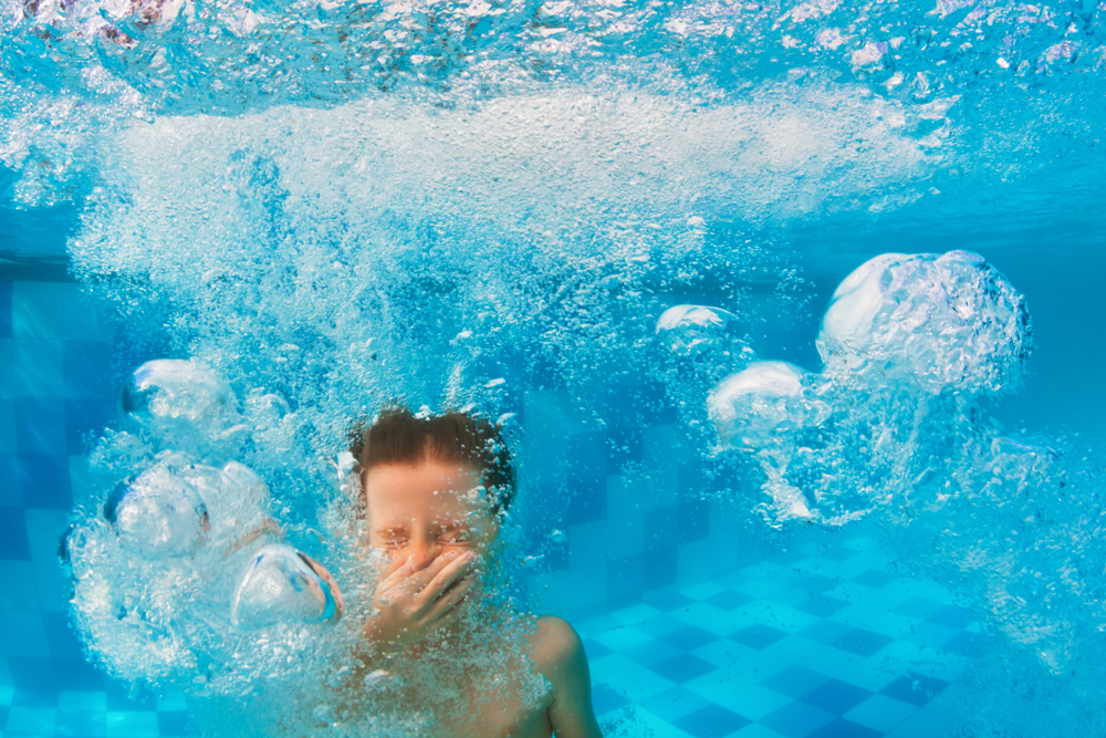 A child underwater with a bunch of bubbles.