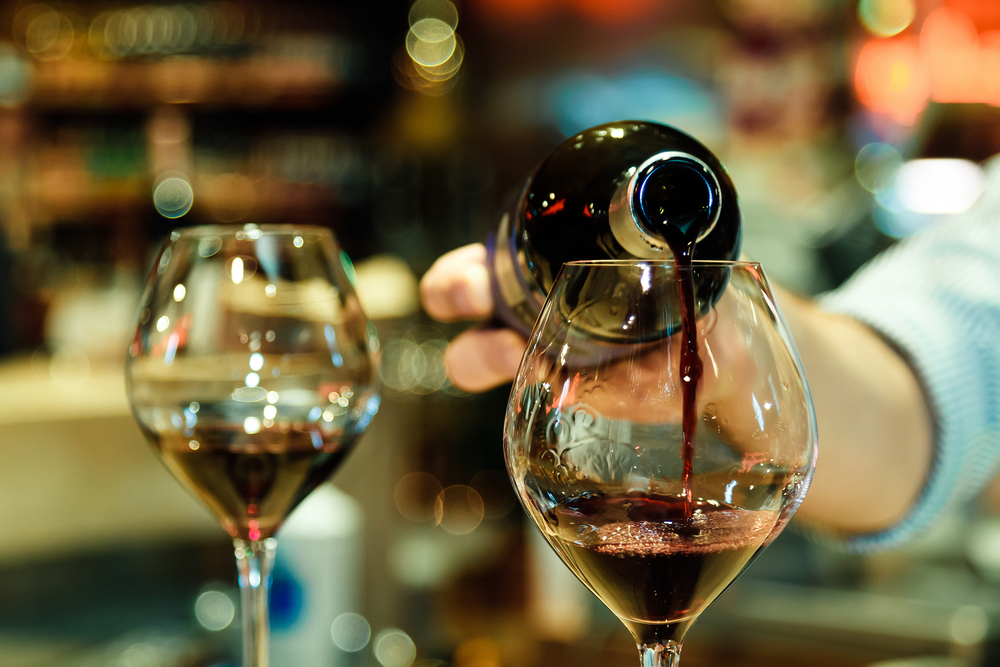 A bottle of red wine being poured into a glass.