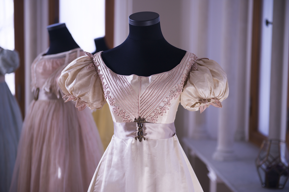 A pale pink and cream silk antique dress on display in an exhibit at a museum