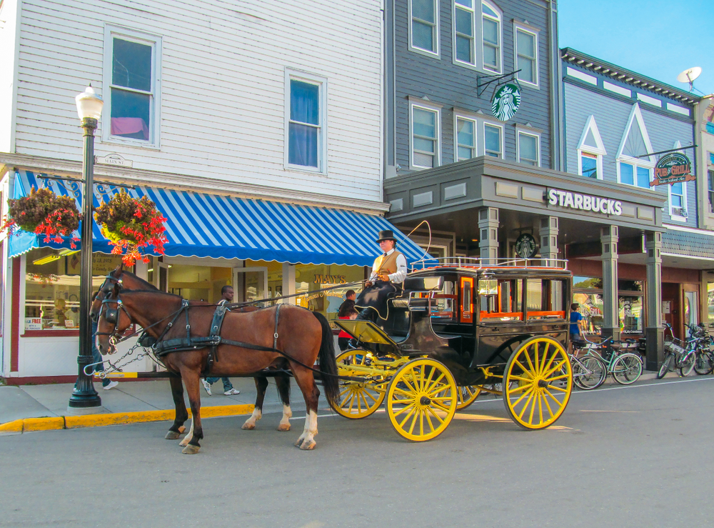 Retro horse Cart with Coachman on the street with old houses in the city center. Mackinac City is one of the beach towns in Michigan.  