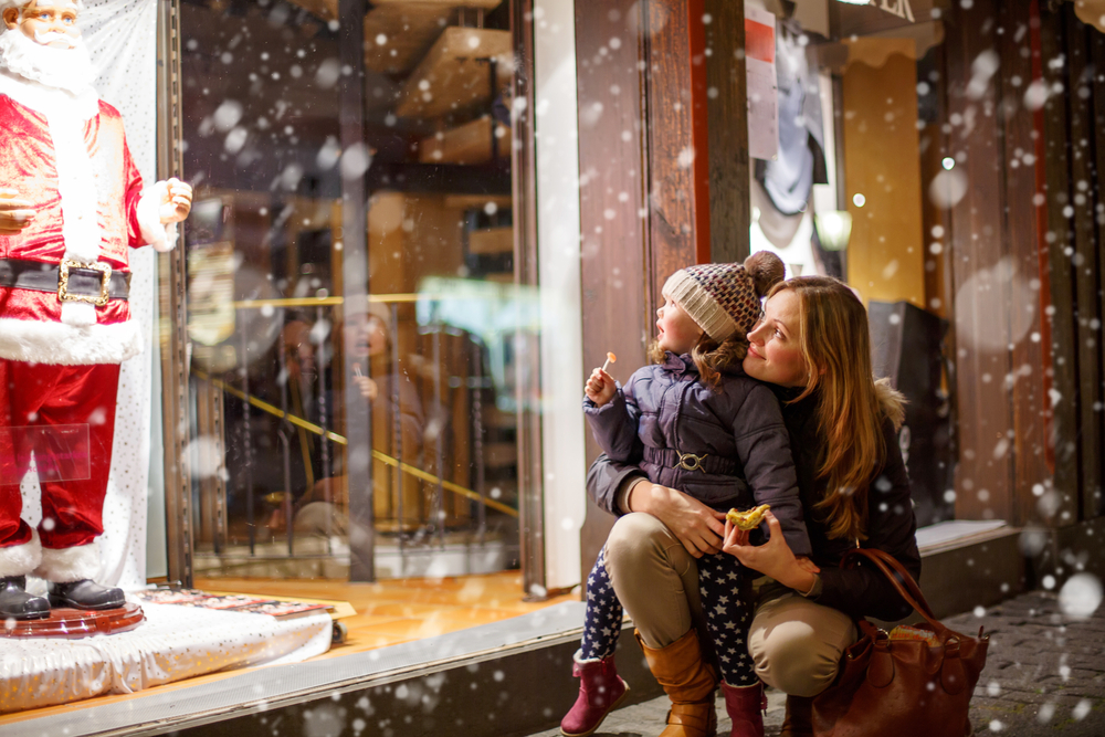A mother and her child looking at Christmas window displays while it snows during Christmas in Branson