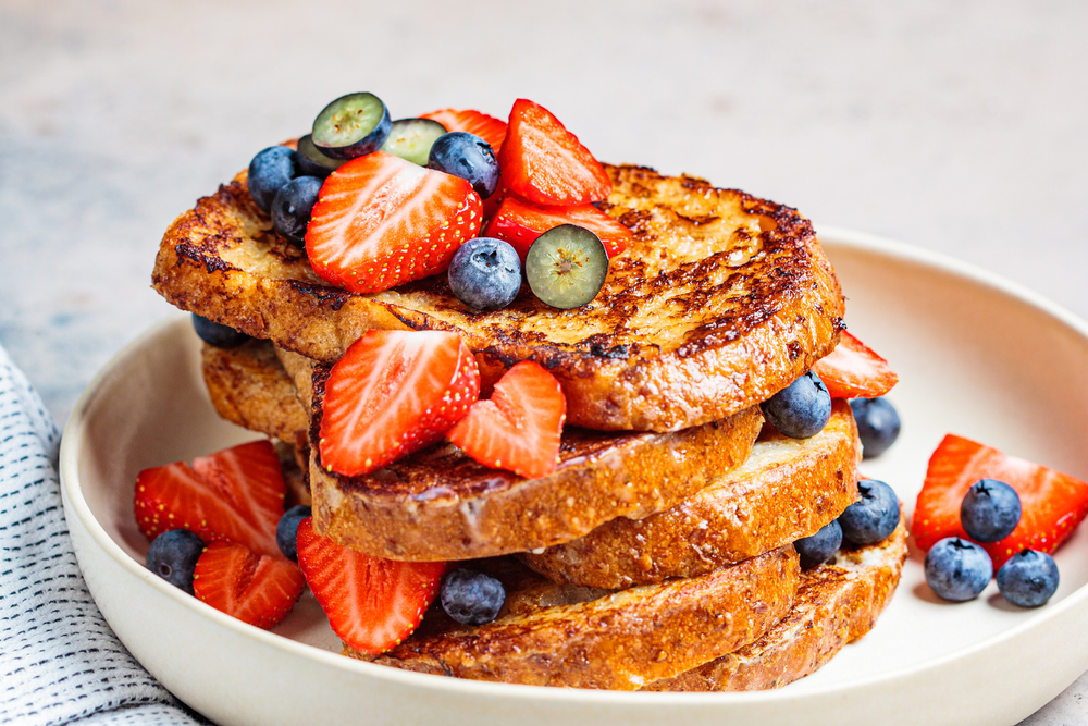 A plate of French toast with fresh strawberries and blueberries. best restaurants in Bloomington