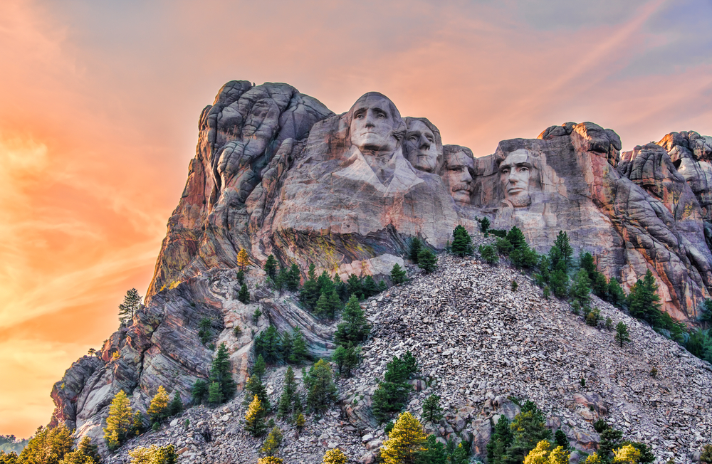A view of Mount Rushmore as the sun sets behind the mountain from a trail for hiking in South Dakota. 