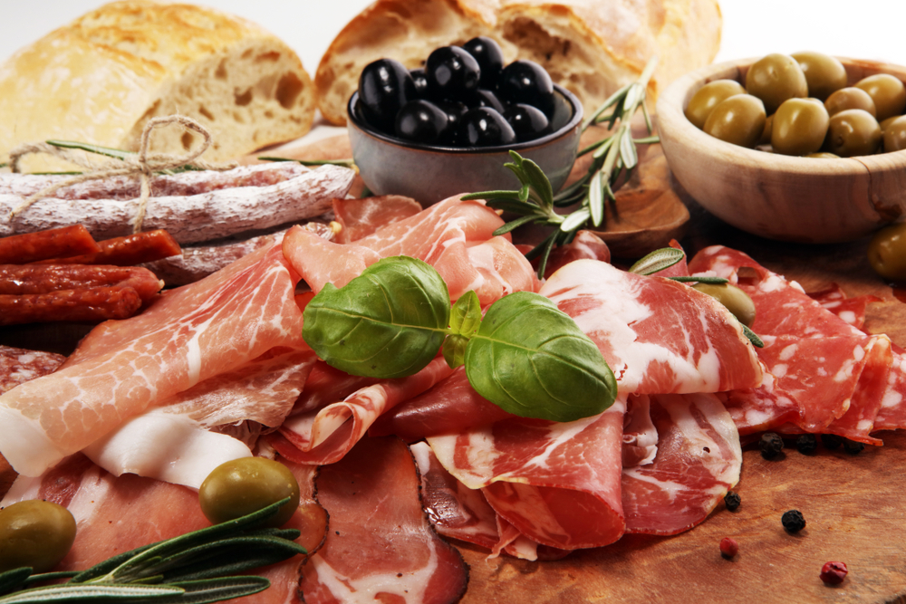 Cutting board with prosciutto, bacon, salami and sausages on wooden background. Meat platter appetizers and olives served at one of the restaurants in Rapid City