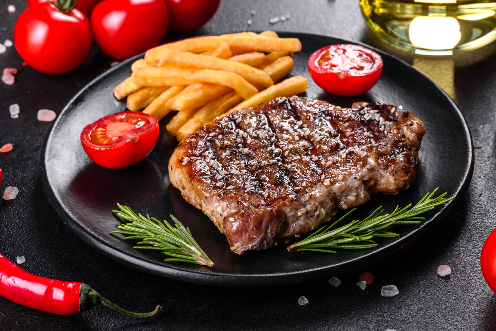 Ribeye steak with potatoes, onions and cherry tomatoes. Juicy steak with flavored butter