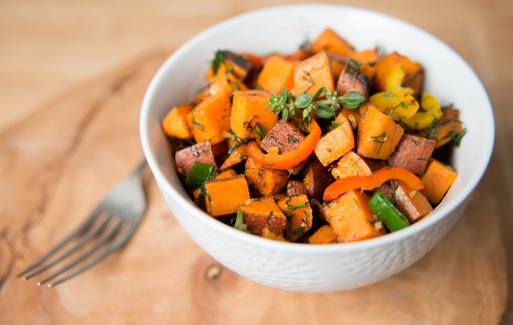 Sweet Potato Hash with Fresh Herbs, Peppers and Onions in a white bowl on a table with a fork by the side. the article is about restaurants in Soiux Falls. 