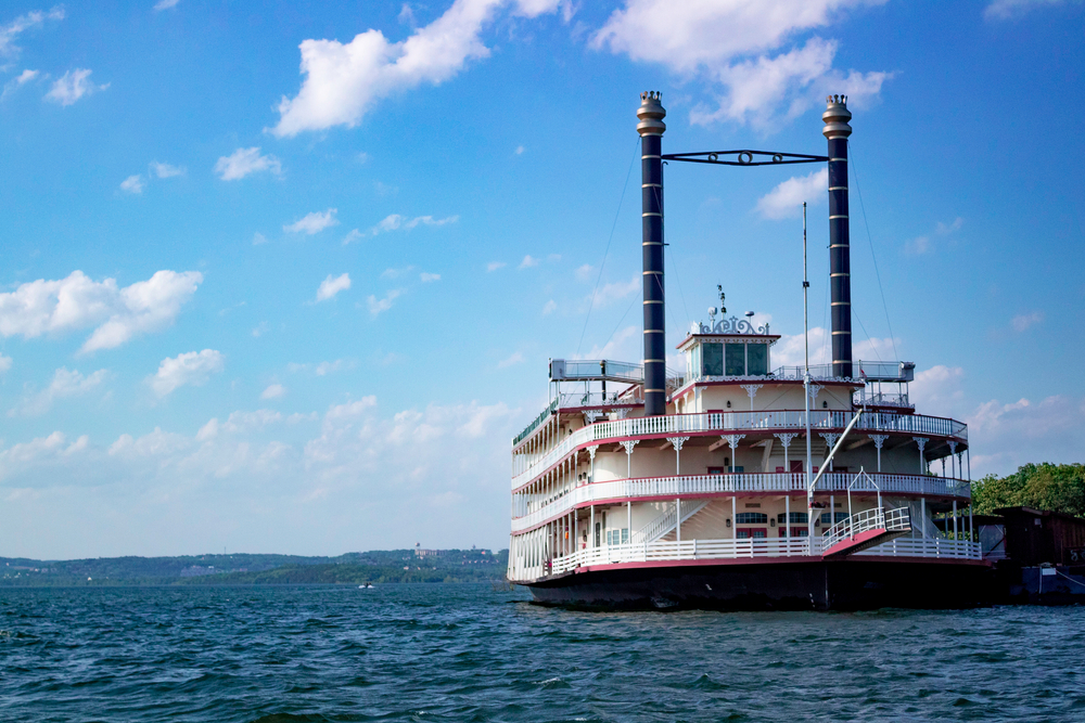 A large white and red steamboat in a river on a sunny day