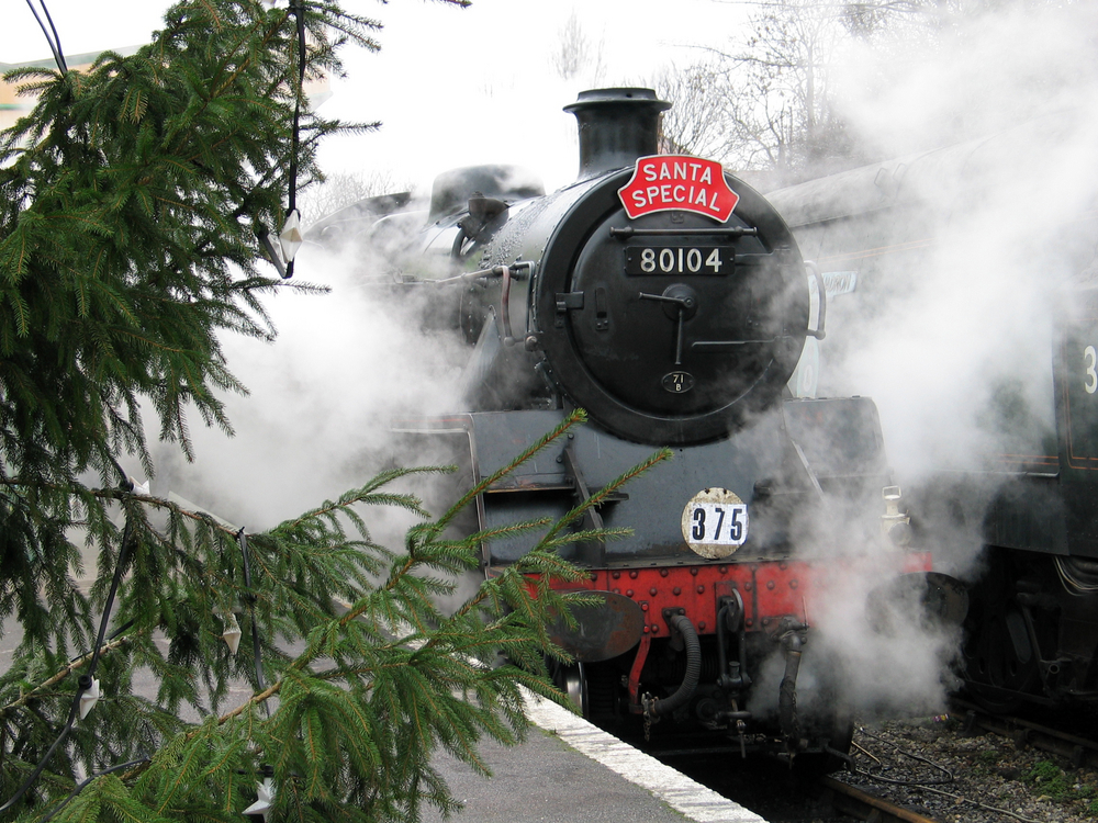 A black train that say's 'Santa Special' surrounded by smoke and evergreen trees during Christmas in Branson