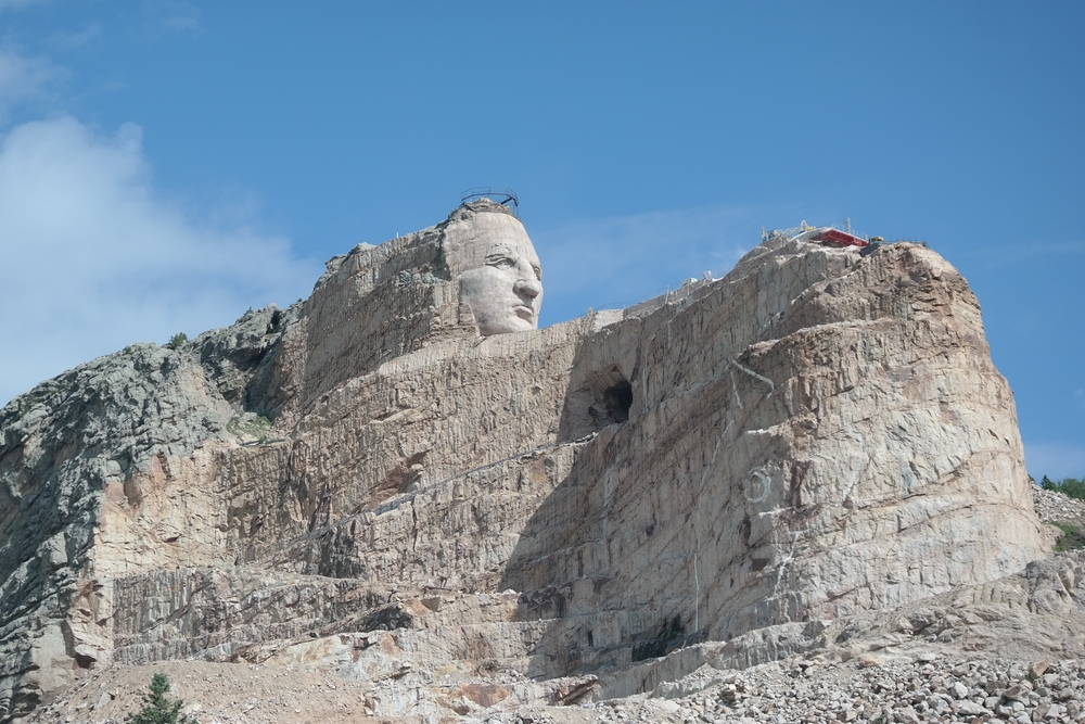 Crazy Horse monument statue in progress. The sky is bright blue 