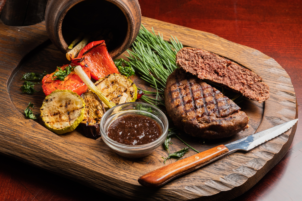 Elk steak with vegetables and rosemary on a wooden board.