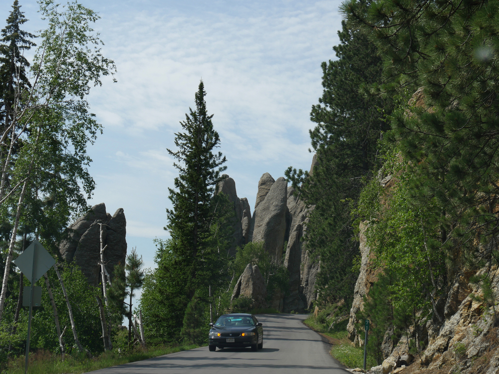 Custer State Park, South Dakota- J A car travels on the scenic Needles Highway just past the Needles Eye
