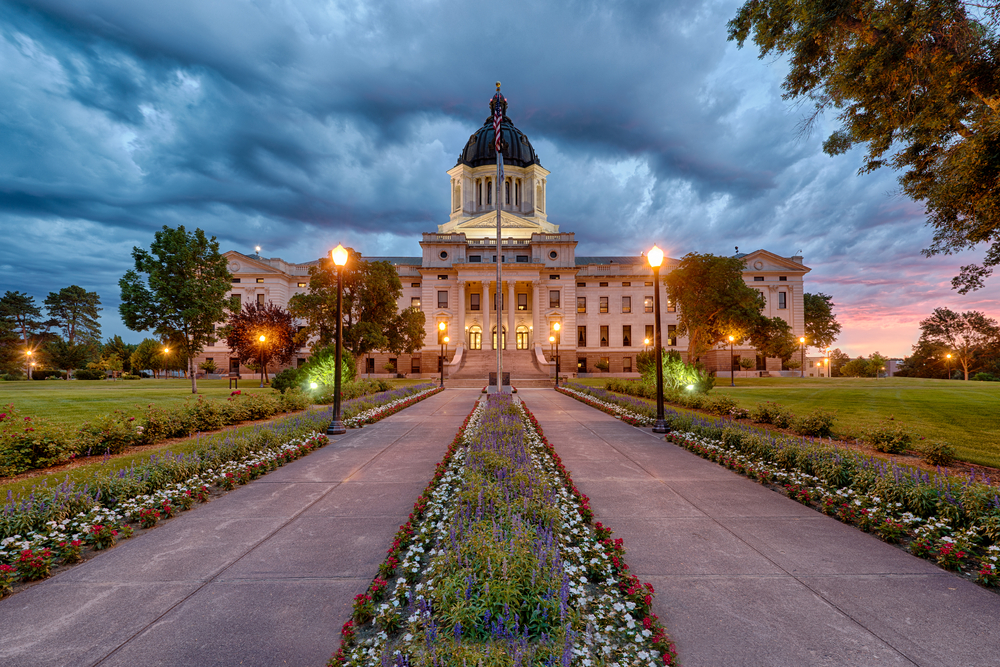 A storm rolls in at dawn at the South Dakota State Capitol building in Pierre, South Dakota. Its a beautiful white building with wonderful flower borders. 
