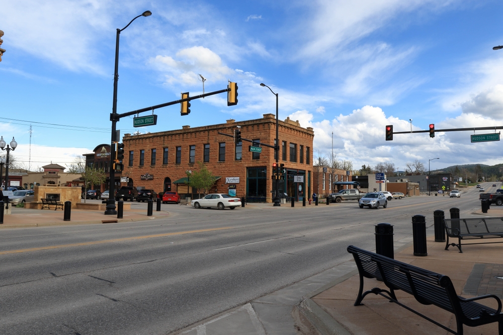 Main street and Hudson street in downtown Spearfish showing a juntion and bench on the sidewalk. 