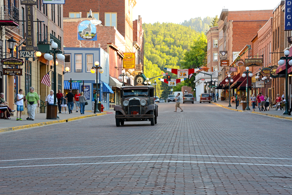 Vintage car approaching on main street in Deadwood in an article about towns in South Dakota 
