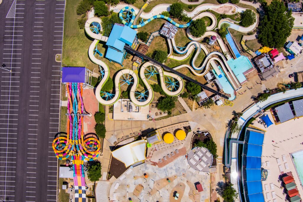 An aerial view of a massive waterpark, similar to Wisconsin Dells waterparks. You can see huge waterslides, pools, a lazy river, and a wave pool. 