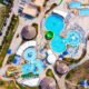 An aerial view of a massive waterpark, similar to Wisconsin Dells waterparks. You can see several pools, waterslides, cabanas, and other water features.