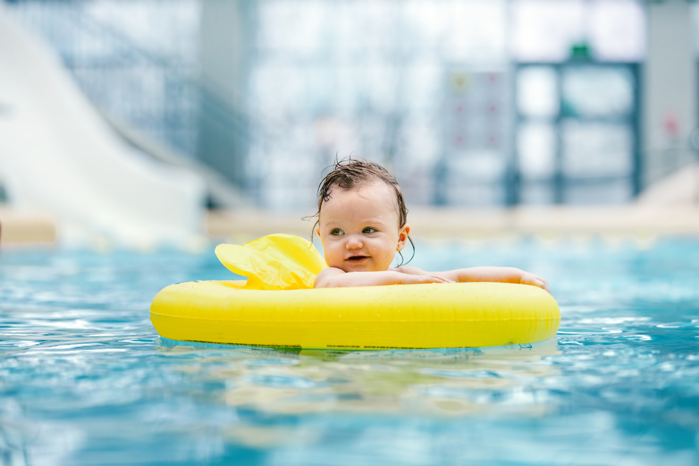 A baby in an inflatable inner-tube at an indoor waterpark for young kids and babies. 