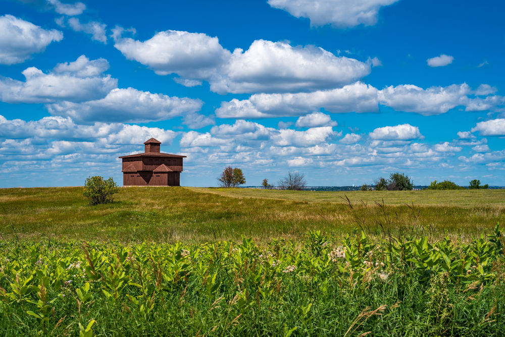 Blockhouse at Fort Abraham State Park the building stands against a blue sky surrounded by grass. 