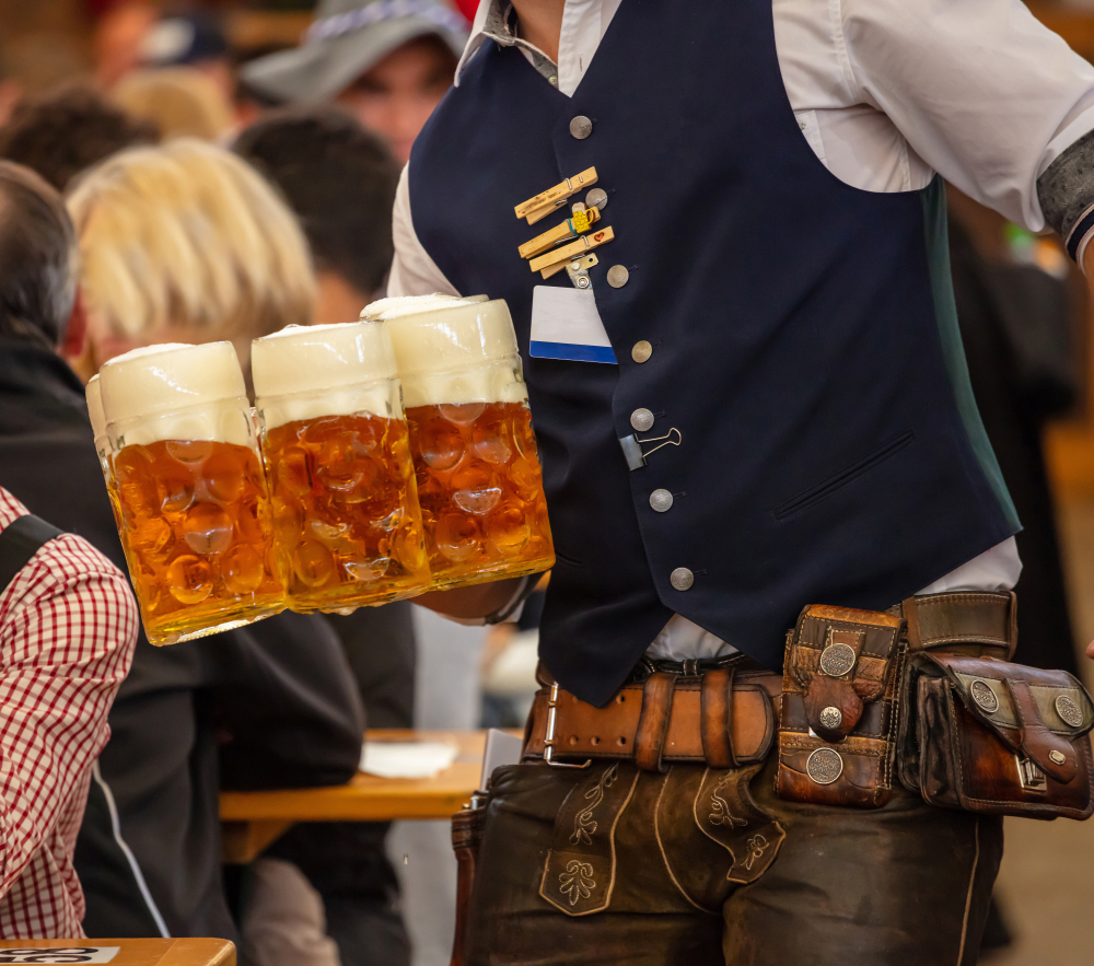 Man in German costume holding big jugs of beer 