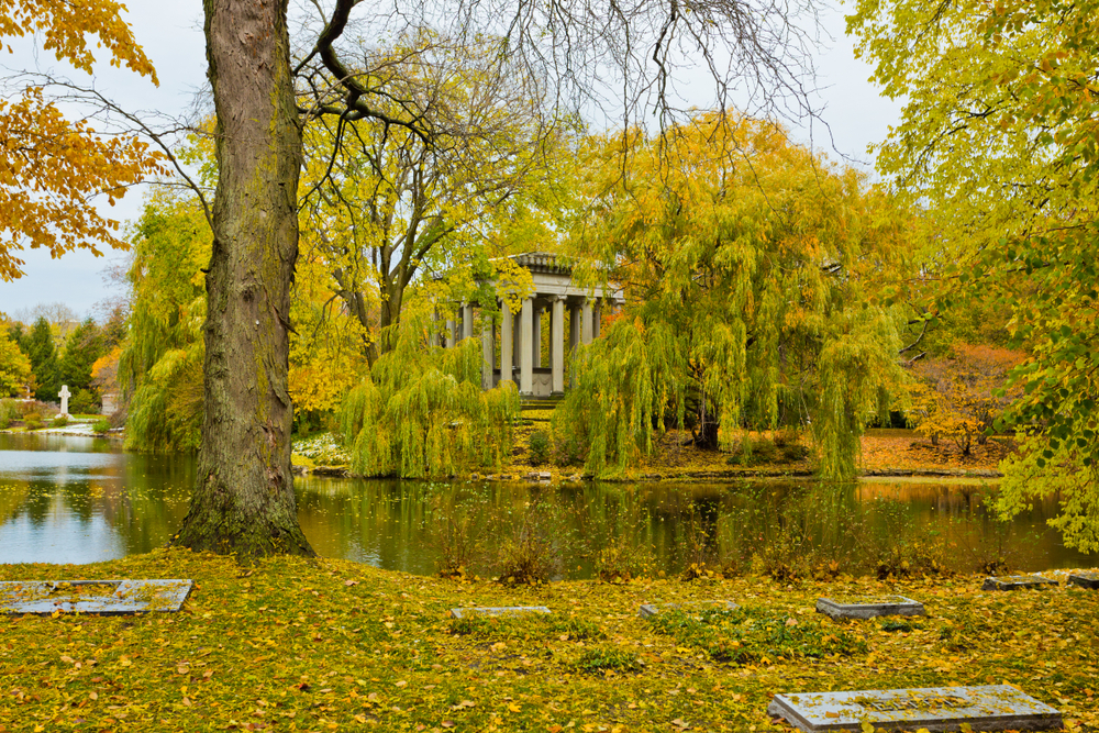 The Graceland Cemetery in the fall in Chicago. You can see a gazebo, tombstones, and trees with yellow, orange, and green leaves.