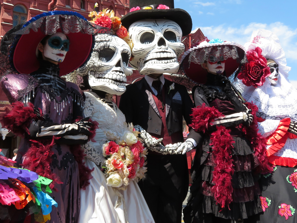 A group of people dressed in elaborate sugar skull costumes, similar to what you can see at a parade in the fall in Chicago.