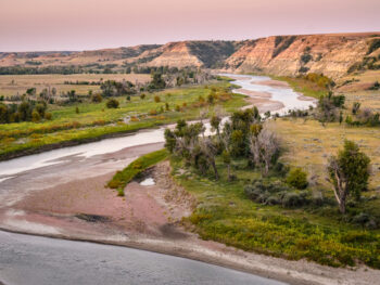 River cutting through prairie with Badlands in background. Hiking In North Dakota