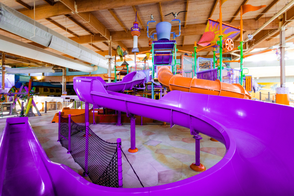 A purple waterslide inside of a large indoor waterpark. 