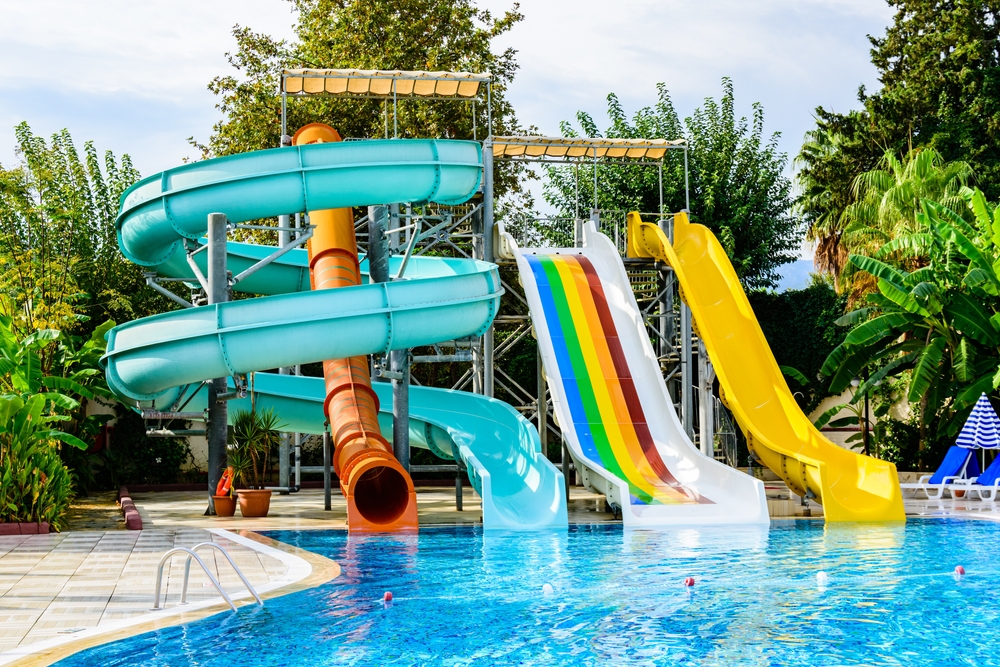 A group of four different kinds of waterslides at an outdoor waterpark surrounded by palm trees and different greenery. 