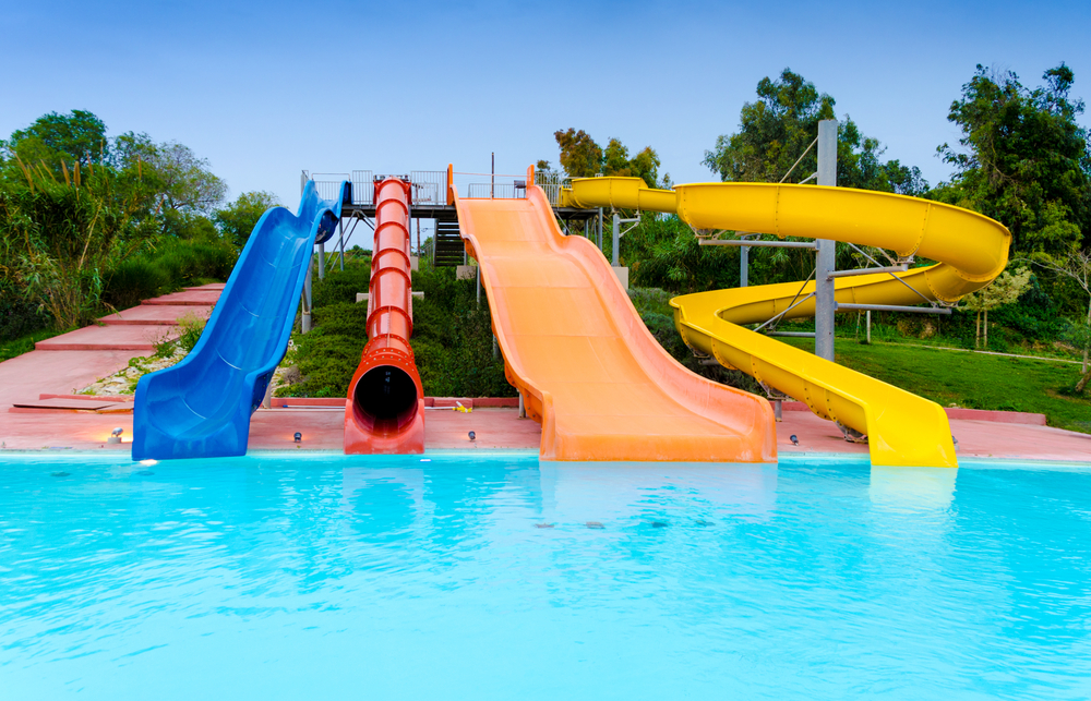 Four small waterslides at a small outdoor waterpark surrounded by trees. 