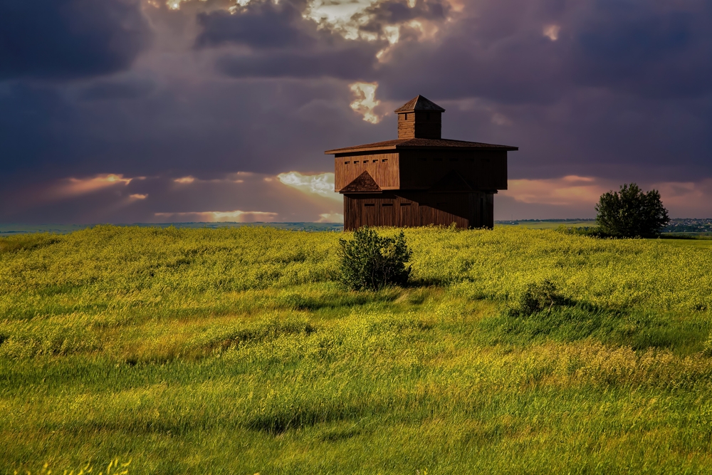 Brown building in the middle of grassland with a dramatic  sky at  Fort Abraham Lincoln State Park 