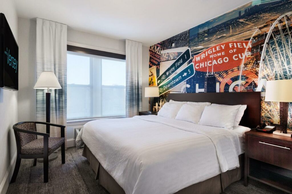 King sized bed in a room at the Hotel Versey Days Inn by Wyndham Chicago with a wall mural of Chicago attractions.