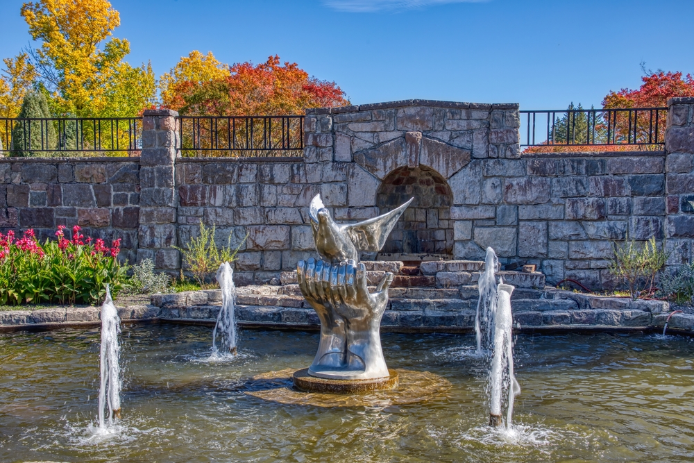 A fountain in the International Peace Garden with a statue of cupped hands holding a dove.