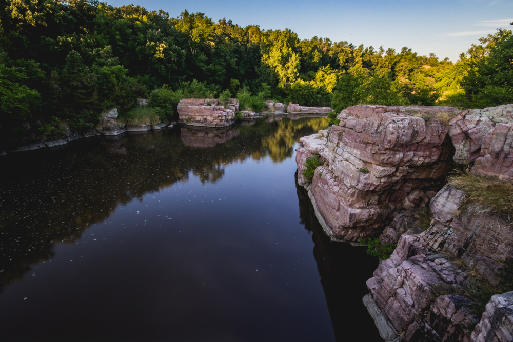 View over the water of cliffs and trees in the background.