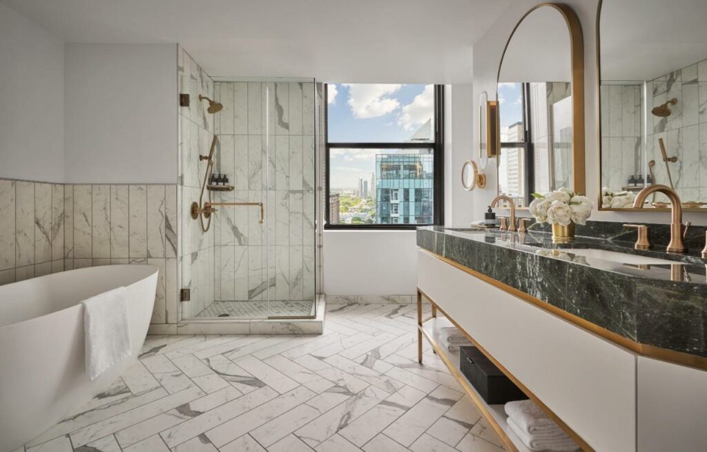 Beautiful marble bathroom at the Pendry Chicago with double vanity, shower, bath, and city views.